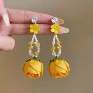 Close-up of yellow rose fabric flower earrings with pearl tassel and rhinestone studs