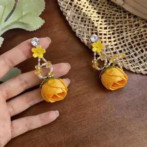Detailed view of yellow rose flower drop earrings featuring rhinestones and beads
