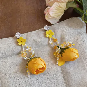 Detailed macro view of yellow rose bud and beaded tassels on floral drop earrings