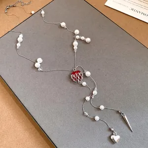 Elegant long faux pearl beaded necklace featuring a unique caged red glass heart pendant
