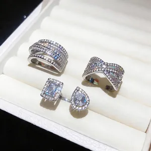 Detailed macro view of three silver zircon rings with cross and open designs in a white box