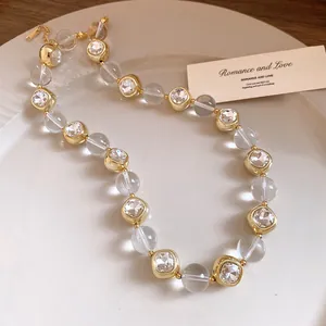 Detailed view of sparkling rhinestones and gold square charms on the elegant beaded necklace.