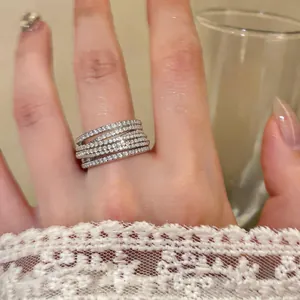 Close-up of multi-layer crisscross zircon ring on finger with lace sleeve detail