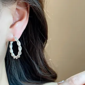 Primo piano di orecchini a cerchio in argento ritorto dal design elegante e minimalista
