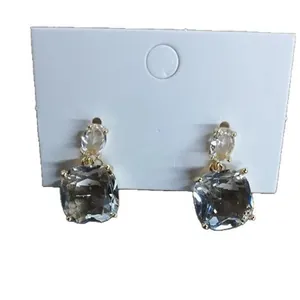 Elegant transparent square zirconia dangle earrings with gold-tone finish on white card.