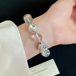 Close-up of minimalist silver beaded bracelet with sparkling rhinestones on wrist.