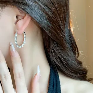Vista dettagliata di orecchini a cerchio in argento con design a spirale su modella
