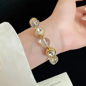 Macro view of gold-toned beaded bracelet with faceted clear crystals on wrist