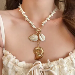 Close-up view of a bohemian style seashell and starfish charm necklace worn by a model