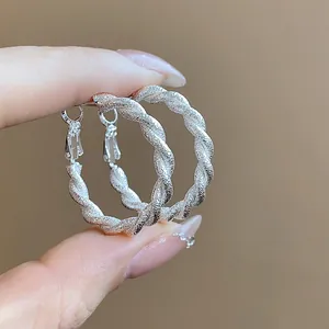 Dettaglio ravvicinato di orecchini a cerchio intrecciati in argento dal design elegante