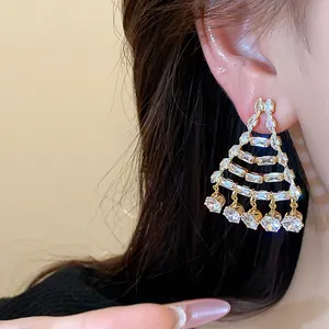 Dettaglio di lussuosi orecchini geometrici a lampadario placcati oro 18k con pietre zircone