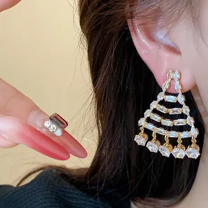 Primo piano di orecchini geometrici placcati in oro 18k con zirconi scintillanti.