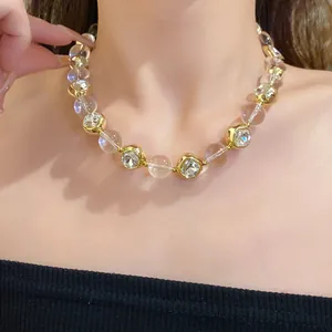 Close-up of elegant gold beaded necklace with sparkling crystal clusters on model