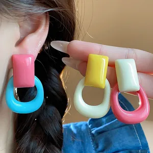 Close-up of colorful resin geometric drop earrings featuring a square stud and round hoop