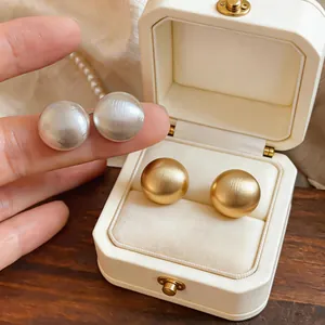 Primo piano di orecchini a lobo tondi minimalisti in finiture oro e argento spazzolato
