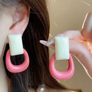 Close-up of pink and cream resin rectangular hollow earrings with silver needle