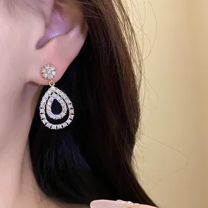 Eleganti orecchini pendenti a goccia placcati in oro 18 carati con zirconi su modella