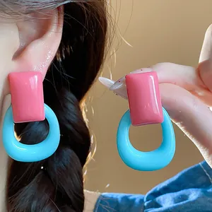 Close-up view showing the vibrant pink and blue resin hoop earrings for a dopamine look