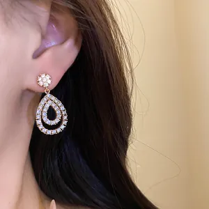 Primo piano dettagliato di eleganti orecchini a goccia in CZ placcati oro 18K indossati