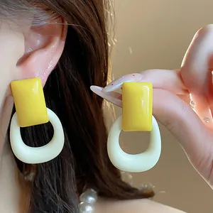 Modern yellow resin hollow square stud earrings with silver needles worn on model