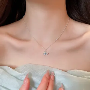 Close-up of elegant flower pendant necklace with blue zirconia on female neck area.