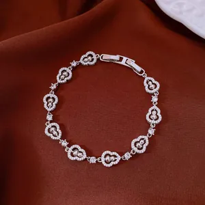 Sparkling silver-tone bracelet with heart-shaped links on brown fabric background