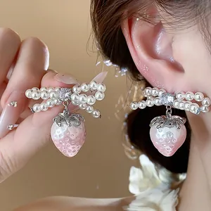 Elegant close-up of sweet pink strawberry and pearl bow-knot earrings for women jewelry