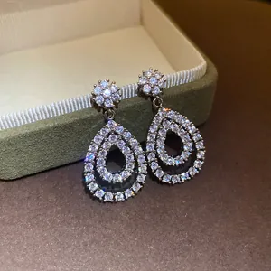 Dettaglio di orecchini a goccia con zirconi scintillanti su portagioie.
