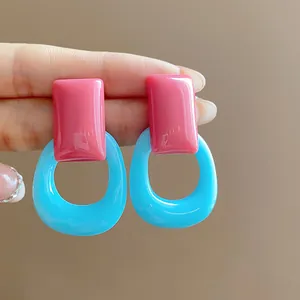 Macro detail of pink and blue resin hollow geometric stud earrings in dopamine style