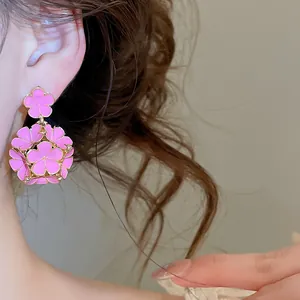 Primo piano dettagliato di eleganti orecchini a fiore rosa smaltati su un modello