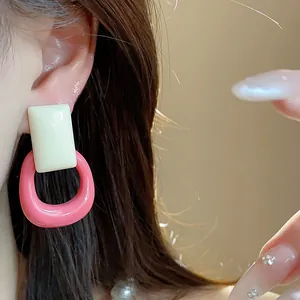 Close-up of minimalist resin square drop earrings in pink and cream on a model's ear