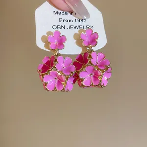Primo piano di orecchini a fiore in smalto rosa con dettagli dorati in stile francese