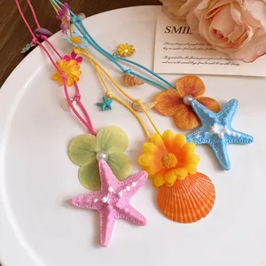Detailed view of colorful starfish, shell, and flower pendants on beach-style necklaces.