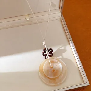 Élégant collier ethnique en acrylique avec pendentif rond marbré et breloque fleur évidée