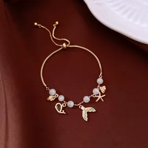 Detail view of a sweet ocean-themed gold bracelet with fish tail and starfish charms.