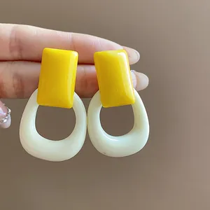 Macro detail of yellow and cream resin geometric stud earrings with silver needles