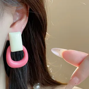 Detailed view of trendy pink and white resin hollow square earrings worn by a model