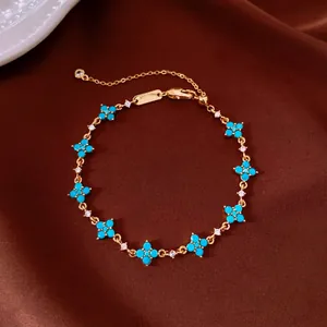 Close-up of gold bracelet with blue flower motifs and crystals on brown fabric