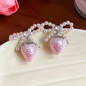 Exquisite detail shot of pearl bow earrings with a sweet pink strawberry pendant
