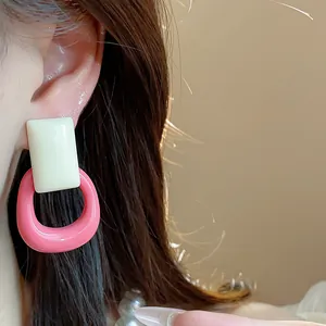 Detailed close-up showing vibrant pink and cream resin geometric earrings on a model's ear