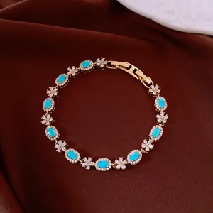 Close-up detail of a gold-toned bracelet with blue oval stones and sparkly crystal flowers.