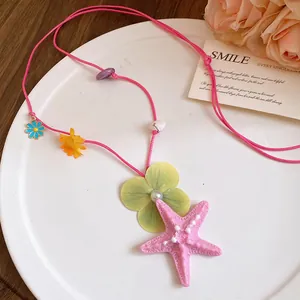 Detailed view of pink cord necklace featuring a large starfish and floral charms for beach vacation
