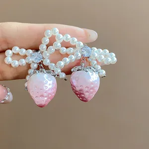 Detailed close-up of handmade pearl bowknot earrings with pink strawberry drops.
