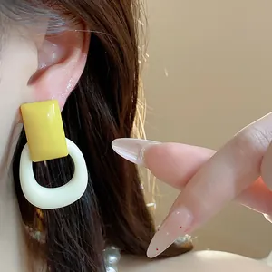 Detailed close-up of stylish yellow and white resin geometric earrings worn on ear