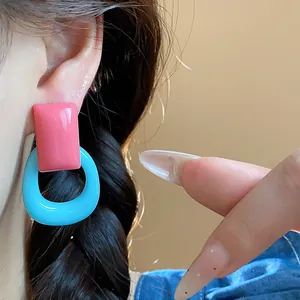 Detailed close-up showing dopamine-style pink and blue resin hoop earrings on a model