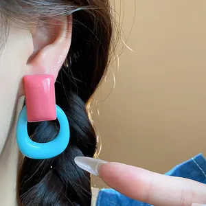 Detailed close-up showing vibrant pink and blue resin geometric drop earrings on ear.