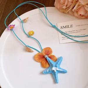 Detailed view of ocean-themed necklace featuring blue starfish, seashell, and flower charms
