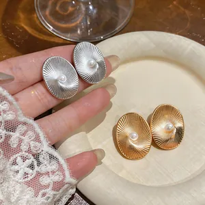 Detailed view of vintage oval earrings with swirled gold texture and a central pearl