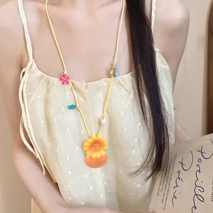 Detailed view of handmade floral and seashell charms on a vibrant yellow vacation necklace