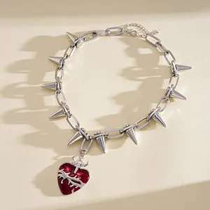 Dettaglio collana punk con borchie argentate e ciondolo a cuore rosso con spine